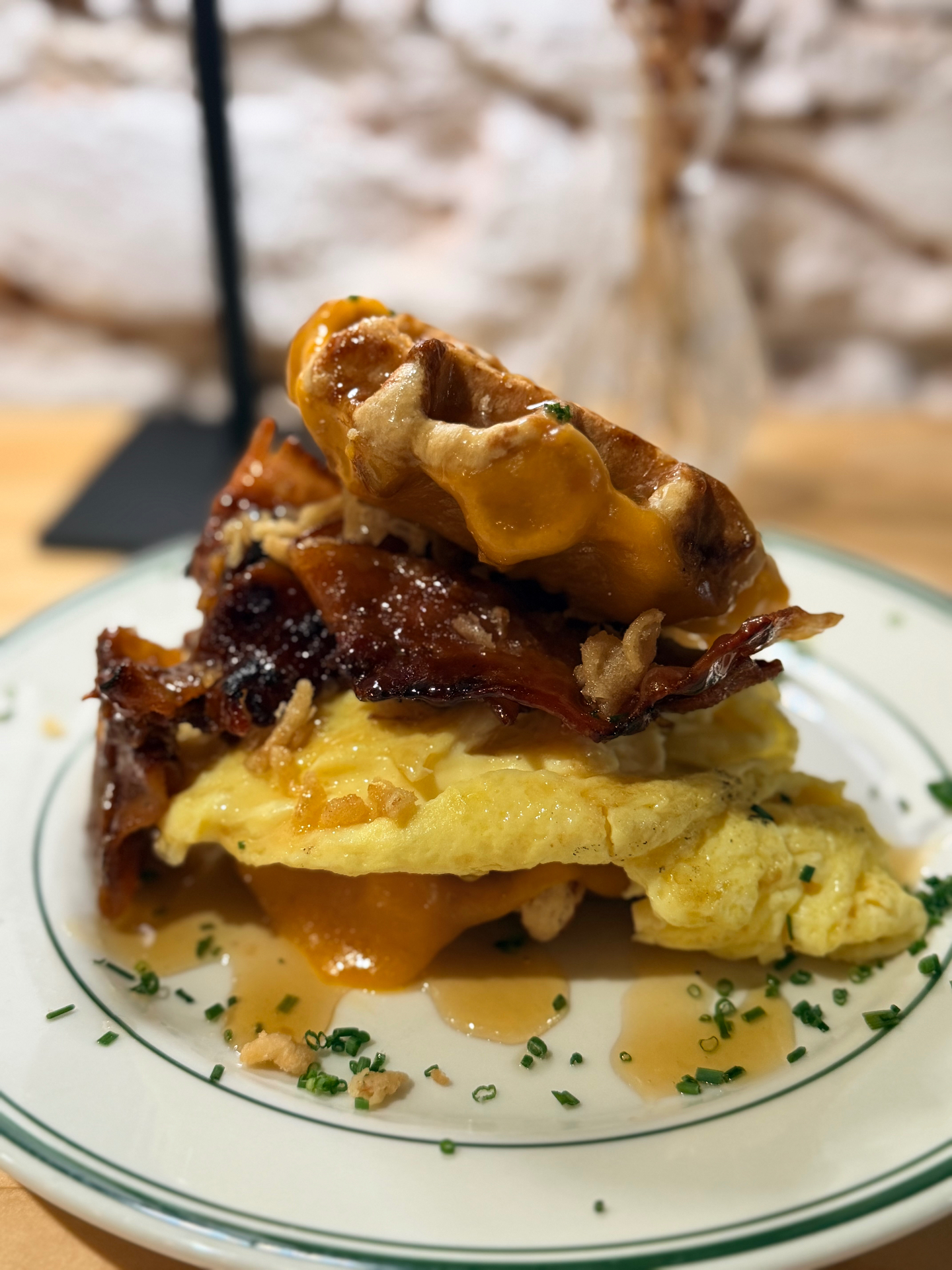 Brü Avl brunch stack: waffle, folded egg omelette, candied bacon and crispy shallots with maple