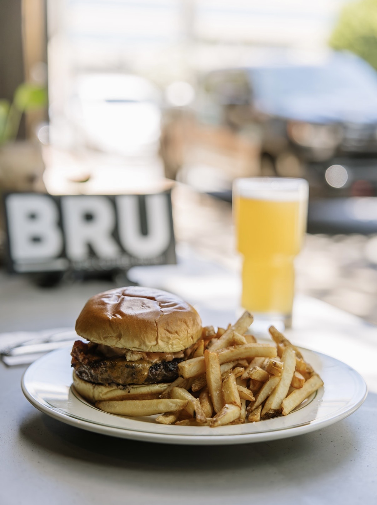 Grilled Brürger with fries and a local draft beer by the window at Brü GastroCafe in Asheville